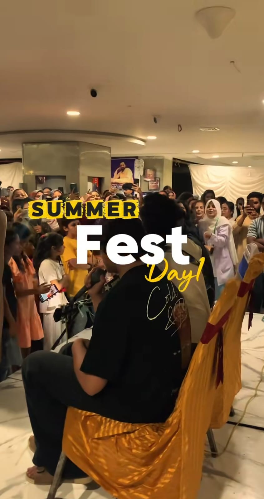 Large crowd of attendees gathered together in a decorated indoor venue during Summer Family Fest, showing enthusiastic and celebratory mood with participants wearing colorful clothing and enjoying the vibrant, festive atmosphere